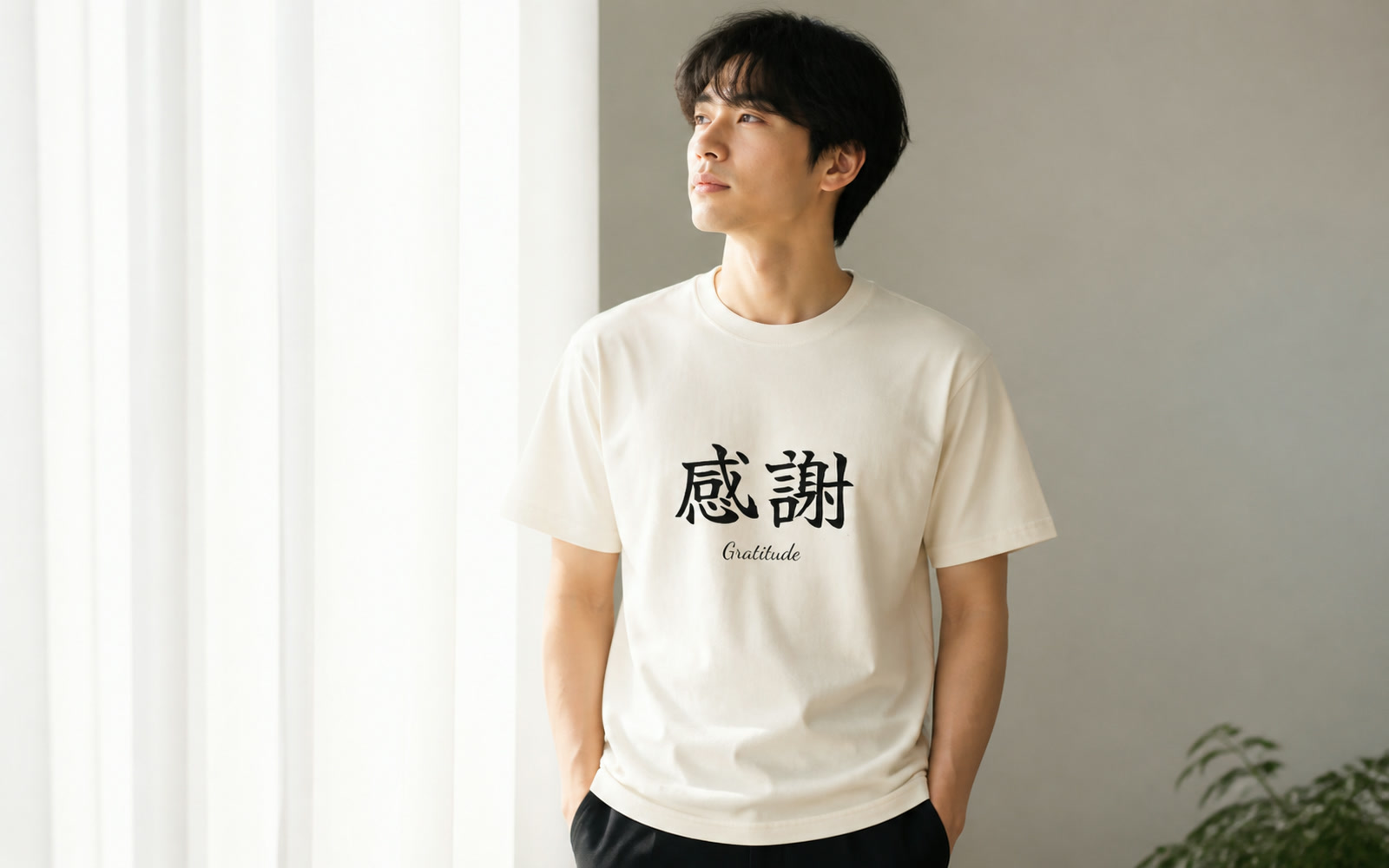 前向きな言葉のTシャツを着た人物が窓辺で物思いにふける写真